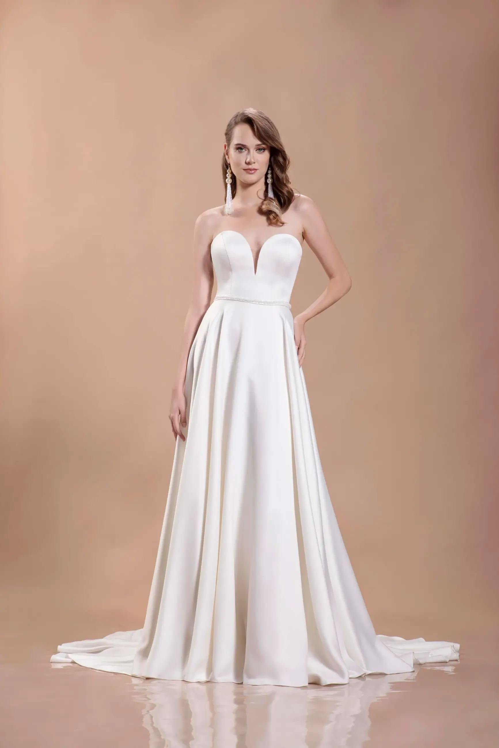 Model is wearing a strapless satin A-line wedding gown with a sweetheart neckline and sleek, minimalist silhouette.