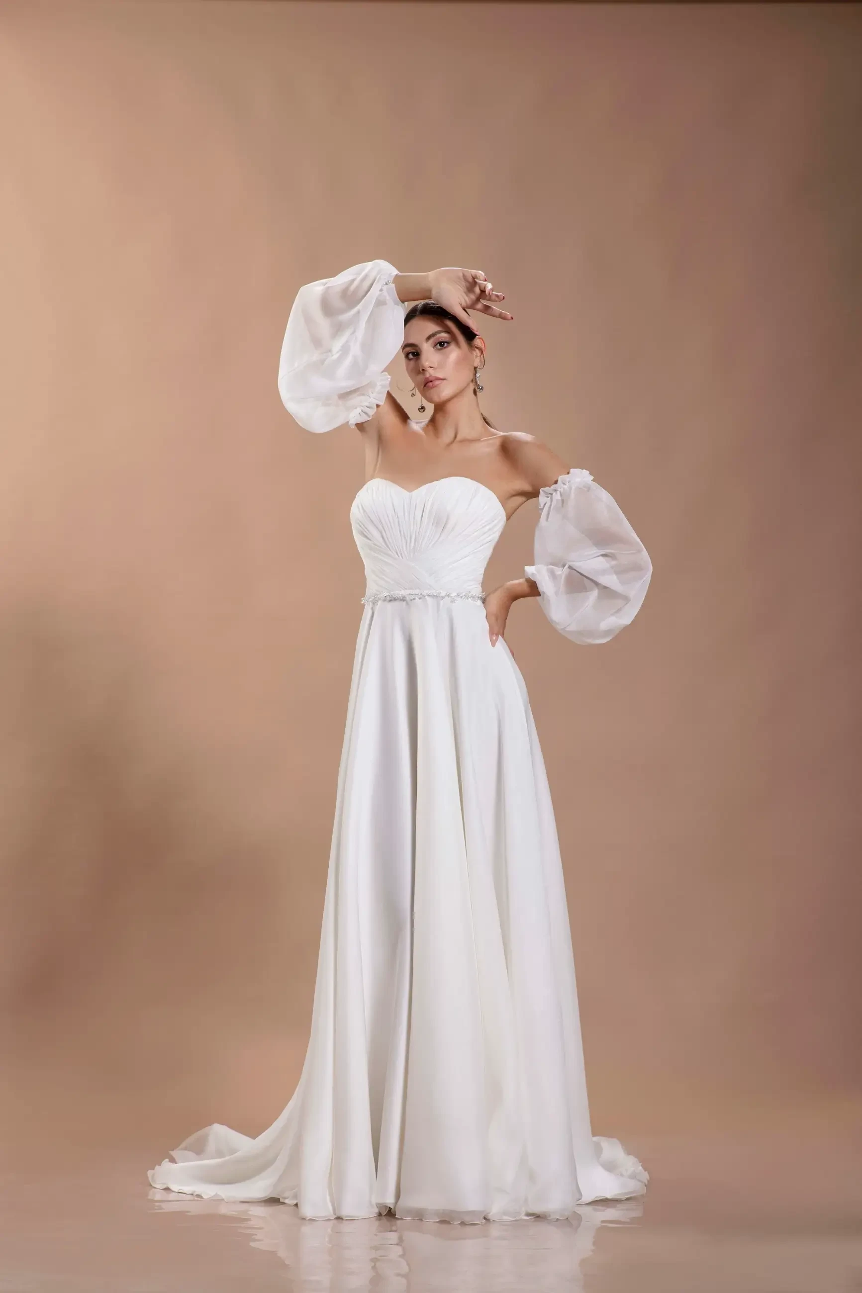 model is wearing an off the shoulder a-line chiffon bridal gown