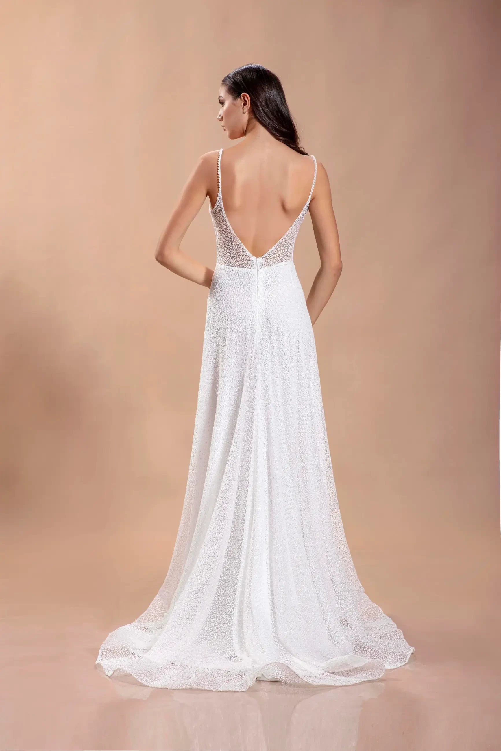 model is wearing a spaghetti strap sleeveless a-line bridal gown with an open back