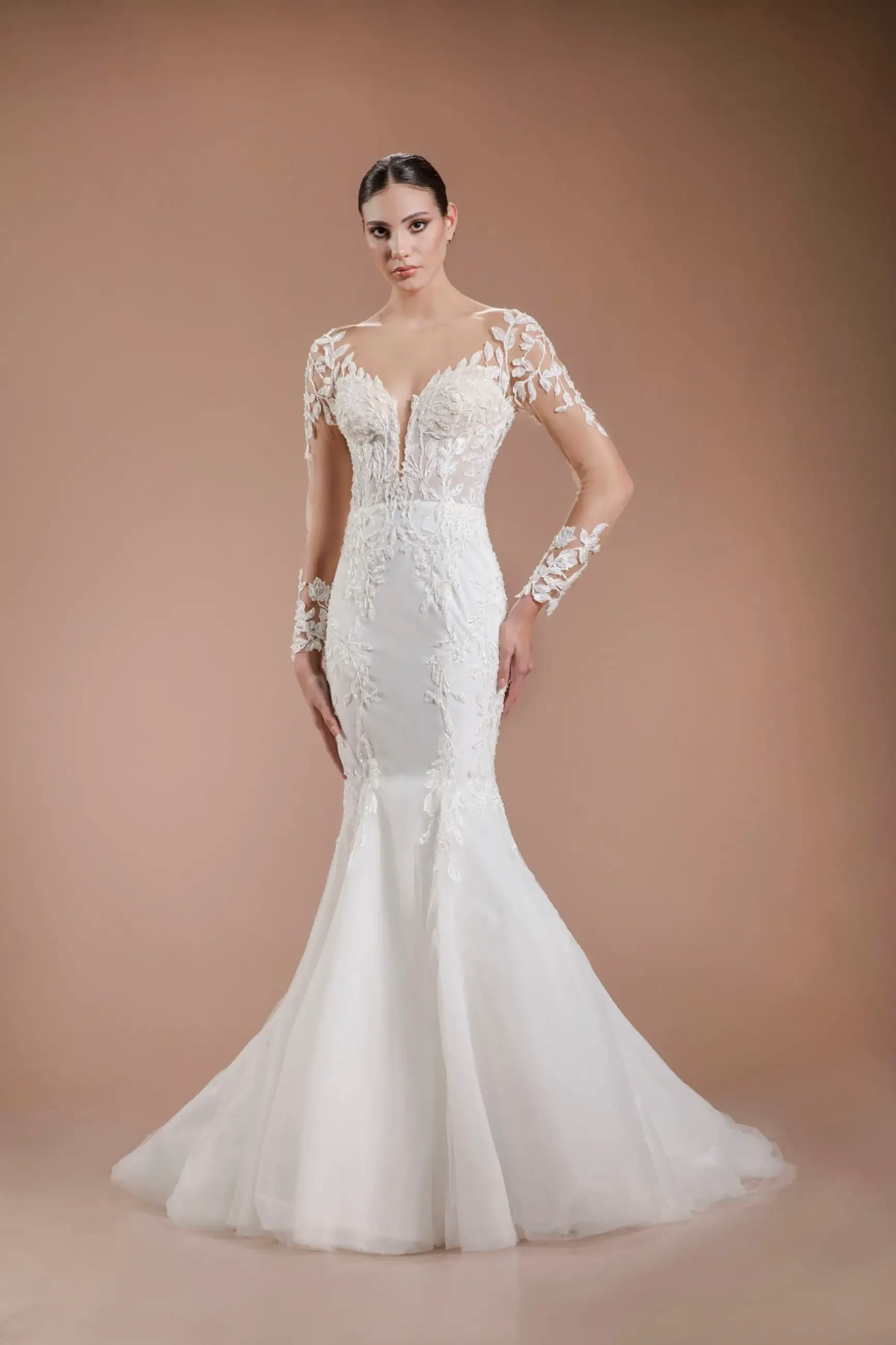 Model is wearing a semi-sweetheart lace wedding gown with delicate lace sleeves, intricate floral pattern, and bead button detailing down the back.
