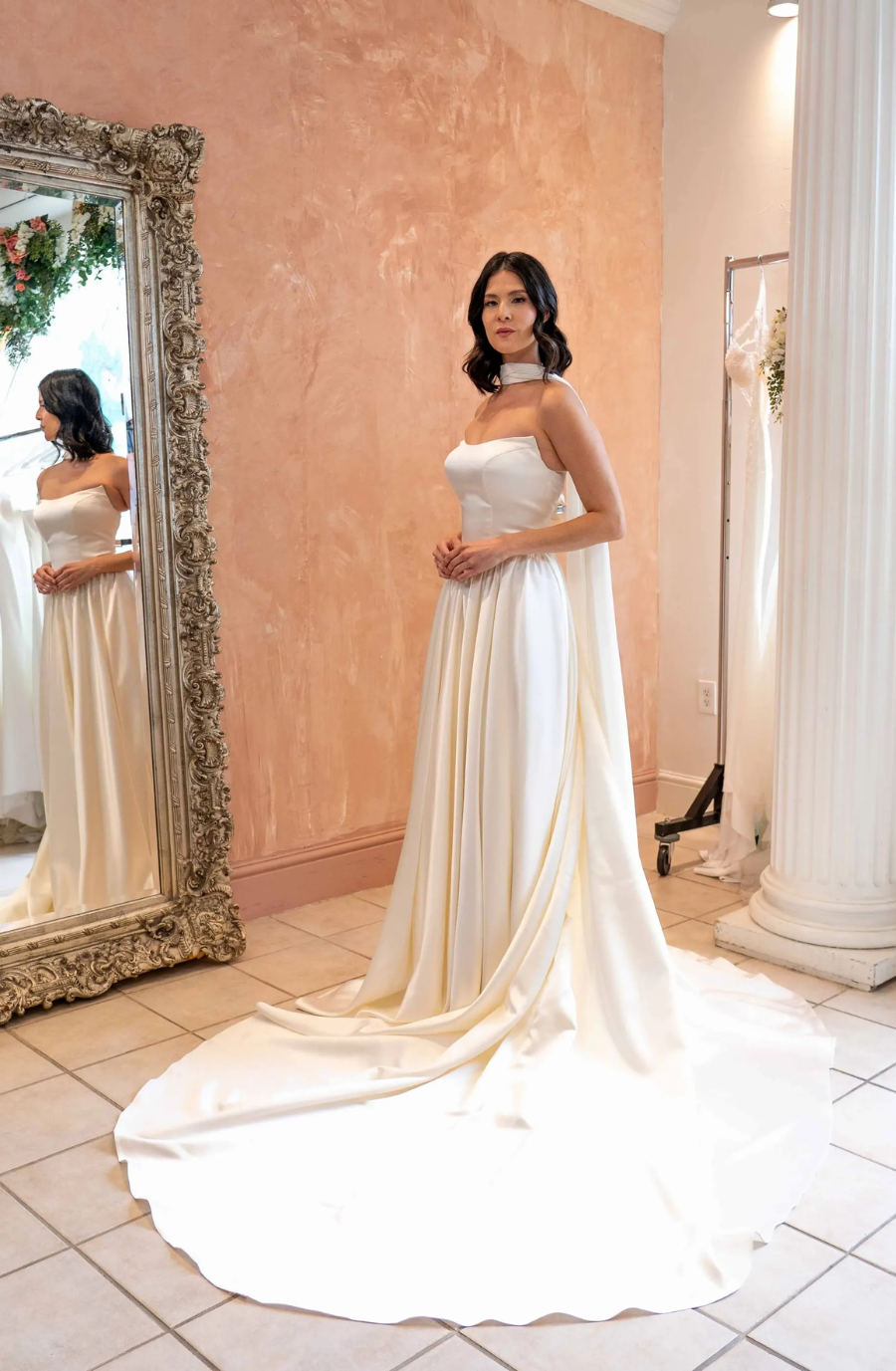 model is wearing a strapless wedding gown with a neck scarf