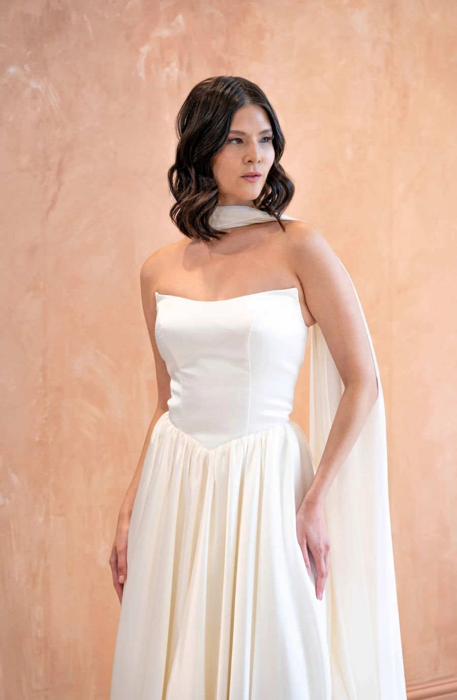 model is wearing a strapless wedding gown with a neck scarf