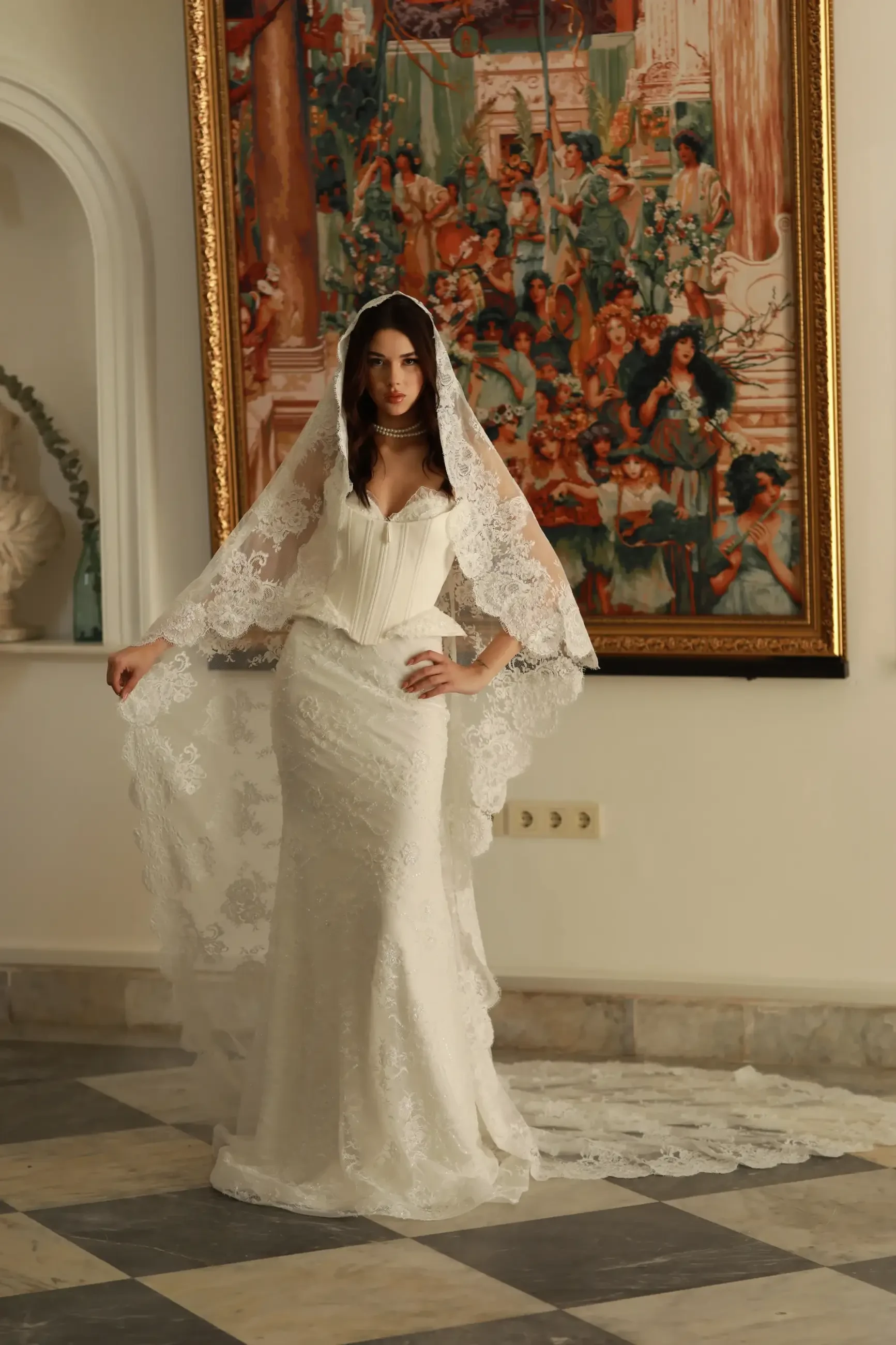 model is wearing a corset wedding dress with lace trimmed veil